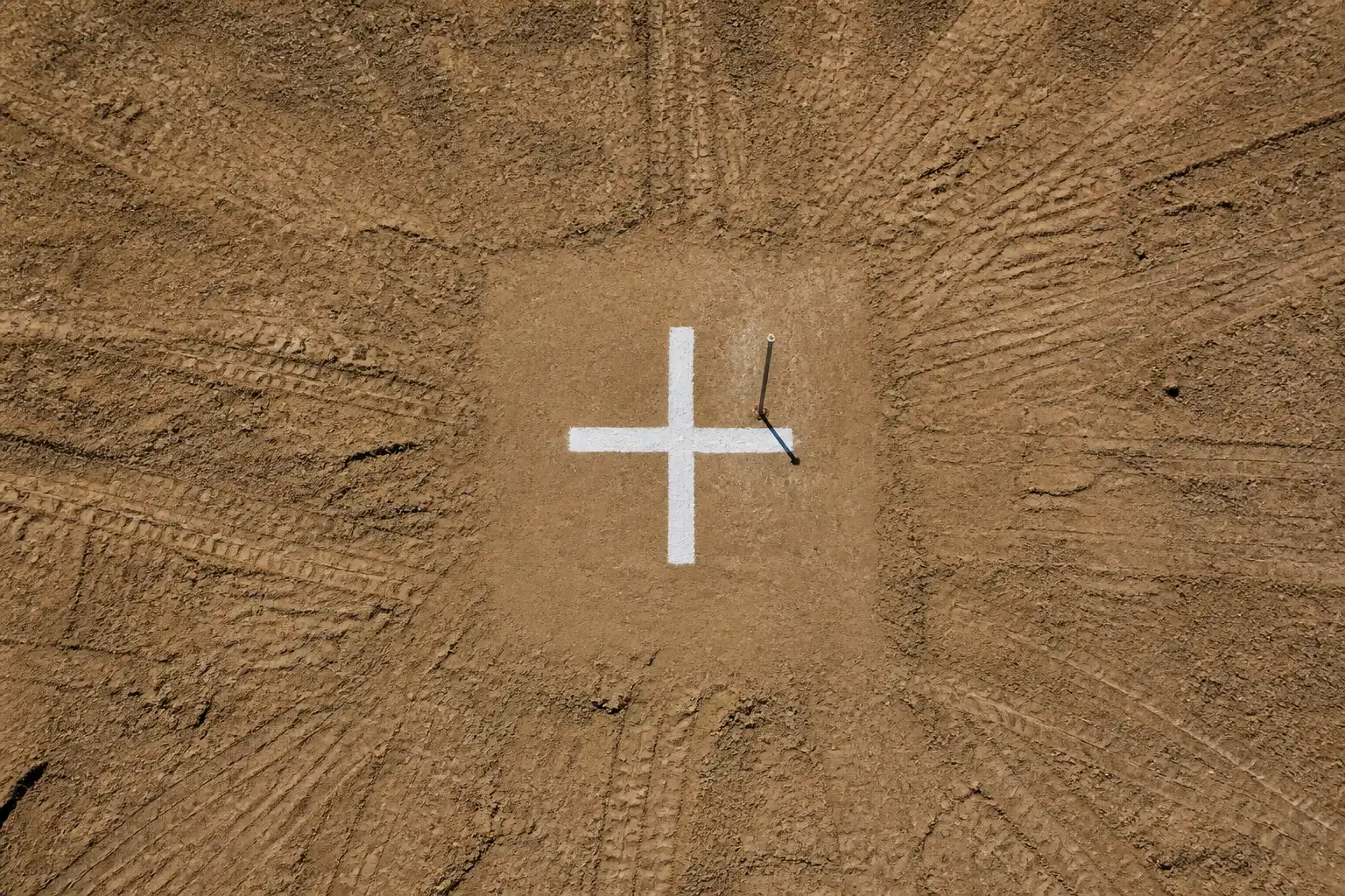 A painted ground control point on a bare earth site, seen from above